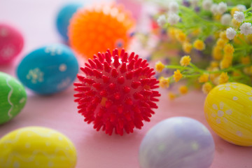 Virus model of Coronavirus disease COVID-19 with colorful easter eggs with flowers on a pink wooden table background