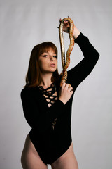 Beautiful woman in black bodywear and snake. Ginger model girl with fashion perfect make up.