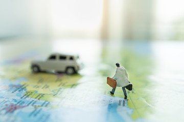 Business Trip and Travel Concept. Close up of businessman miniature figure with handbag suitcase running on colorful world map to mini white car with copy space. - Powered by Adobe