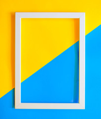 Abstract colored yellow and blue paper texture minimalism background. Minimal geometric shapes and lines composition with empty white picture frame. Free copy space.