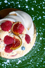 Close up of dessert Pavlova with raspberries and figs on green plate. Top view