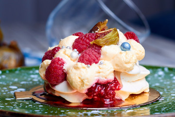 Close up of dessert Pavlova with raspberries and figs on green plate