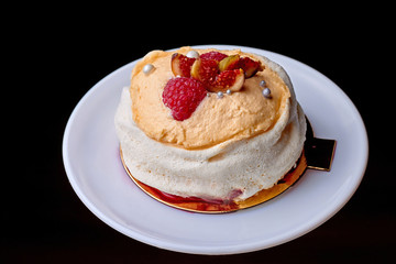 Close up of dessert Pavlova with raspberries and figs against a dark background