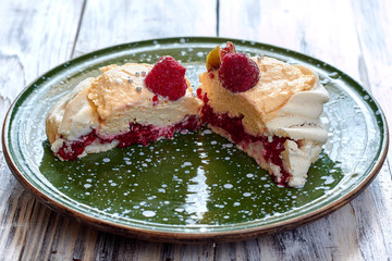 Сut of dessert Pavlova with raspberries and figs on green plate. Close up.