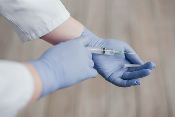 Fototapeta premium doctor in white coat and gloves holds a syringe with a vaccine