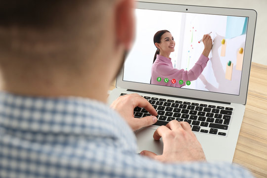 Young man watching video at desk, closeup. Online learning