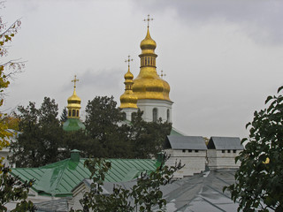 Fototapeta na wymiar Golden domes of the Church of the Exaltation of the Holy Cross in nearby caves in the Kiev Pechersk Lavra in the rain