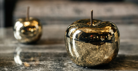 Two golden apples lie on a marble table. Decoration.