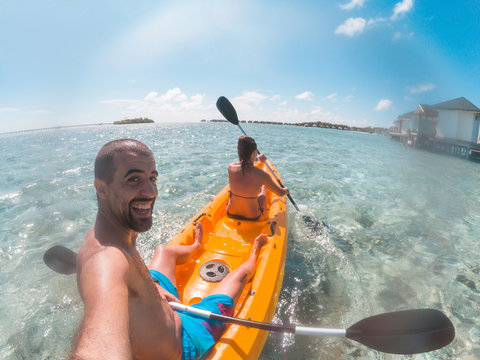 Couple on a kayak at Maldives seaside resort - Young happy couple enjoying summer vacation and having fun in a canoe on the water - Summer and sport concepts
