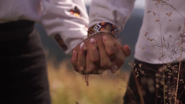 Young couple holding hands, mountainous terrain, dry grass