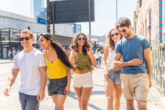 Multiracial group of friends together in the city - Multi ethnic group in London, walking on pavement on a sunny day and laughing - Friendship and lifestyle concepts