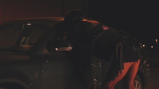 Prostitute talking with client on the street at night. Transgendered prostitute. Transvestite prostitute