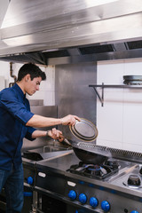 Young chef cooking in a modern restaurant kitchen