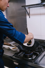 Young chef cooking in a modern restaurant kitchen