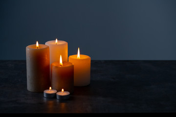 Candle lights in the darkness. Some candles burning in dark background.