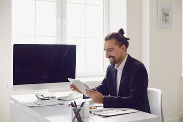 Fototapeta premium A businessman in a black jacket works analyzes strategy at the computer in the office.