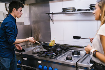Young couple chef cooking in a kitchen in a modern restaurant