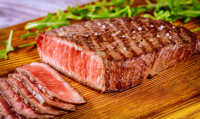 Delicious and healthy grilled medium rare beef steak on wooden board.