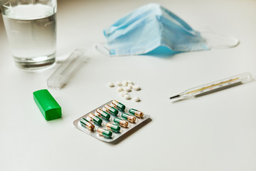Mercury thermometer high temperature, white round medicine pills and medical mask. Flu virus, pneumonia concept. Covid-19, coronavirus.