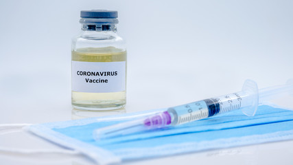 Vaccine and syringe injection for Covid-19 on face mask in scientific laboratory