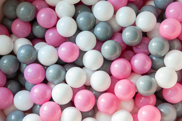 Top view of pink, grey and white plastic balls in the pool. Kids playground