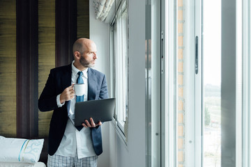 Fototapeta premium Businessman by the window with laptop and coffee