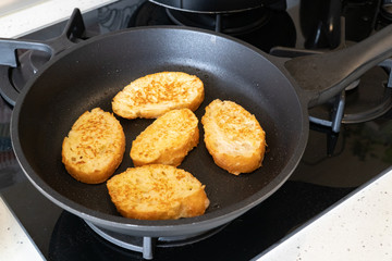 Bread croutons in an egg are fried in a pan. Close-up. Top-side view
