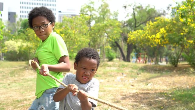 African American serious boy and girl pulling a rope together in tug of war competition - brother and sister on leisure activity on weekend