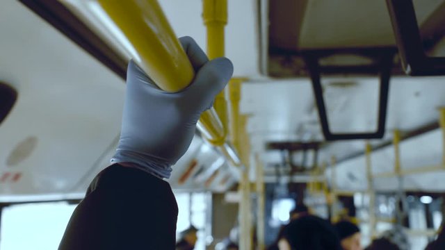 A man rides in a public transport and holds a handrail in his protective medical squirt. Coronavirus infection and epidemic protection concept, pandemic