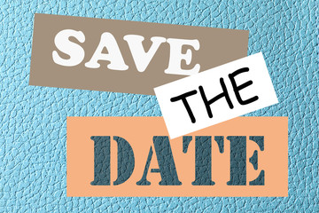 Phrase SAVE THE DATE on light blue leather, top view
