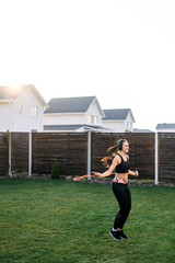 Young woman jumps with a skipping rope outdoors
