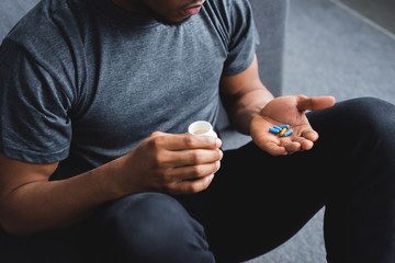 cropped view of african american man taking pills at home