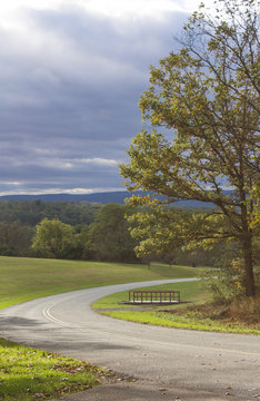 A country road in the Appalachian Mountains on a cloudy fall day with a break in the clouds shining light
