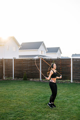 Fototapeta premium Young woman jumps with a skipping rope outdoors