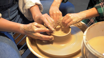 Boy and woman works with pottery wheel in a workshop