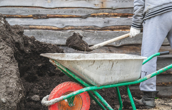 Man use sholve to load solid in wheelbarrow for garden work 