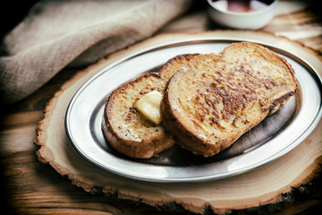 Two pieces of French toast with a pat of butter. 