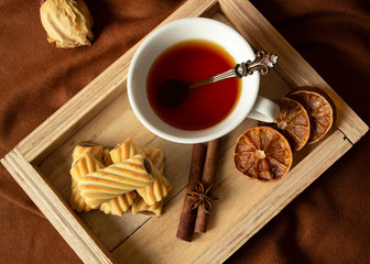 Cup with tea and cookies on a wooden tray flat lay