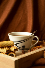 Cup with tea and cookies on a wooden tray with copy space.
