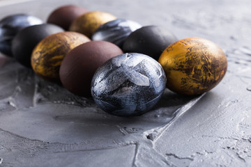 Holidays, traditions and Easter concept - Dark stylish easter eggs on grey background.