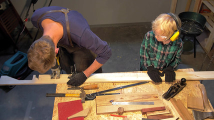 Slow motion, boy helps man in apron in the workshop