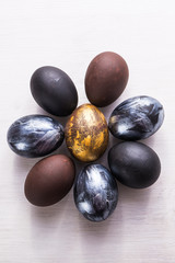 Holidays, traditions and Easter concept - Dark stylish easter eggs on white wooden background.