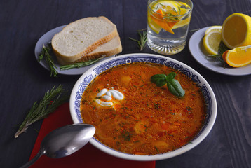 Traditional Russian and Ukrainian borsch, red soup with bread on a dark background. Borsch with meat, sour cream and dill. Overhead Copy Space