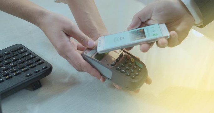 Side shot of hand using paying application on smartphone - payment is approved with tick or checkmark.