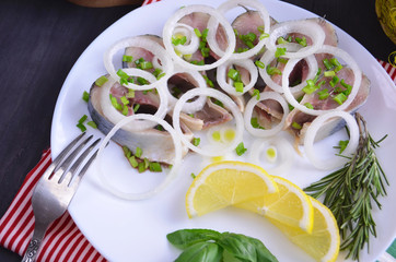 Herring fillet with salt, pepper, herbs, onion and lemon on black plate on white background. top view. healthy food