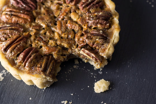 Close Up View Of A Mini Pecan Pie With A Bite Missing. 