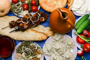 Traditional Georgian cuisine. Georgian dishes and wine jug. Top view of Georgian cuisine food set from khachapuri, kinkily, shot, roasted meat, fresh vegetables and wine.