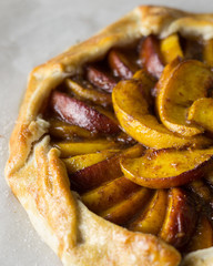 Close up view of a rustic peach tart on parchment paper.