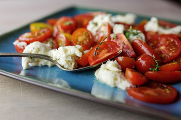 Close up of caprese salad with sliced cherry tomatoes and buffalo mozzarella. 