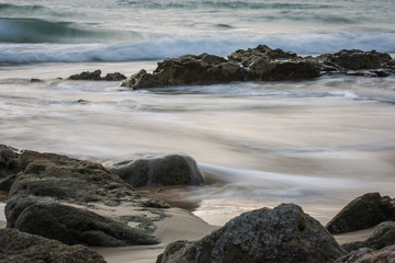 Long Exposure Shot of Rocks on a Beach with Ocean Waves during Daylight